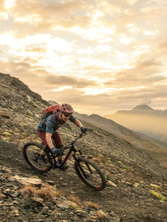 Mountainbiker fährt Trail in den Bergen um Scuol im Sonnenuntergang