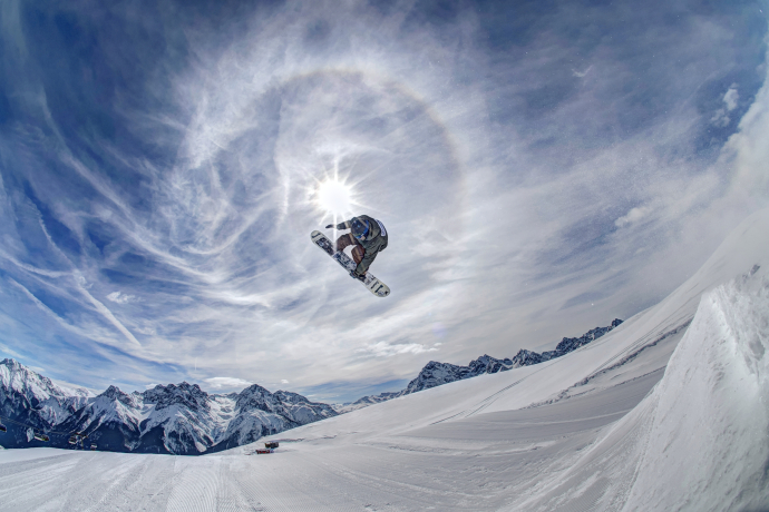 Snowboarder im Sprung mit Sonne im Hintergrund