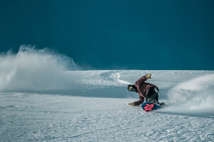 Snowboarder carvt im Skigebiet Scuol Motta Naluns