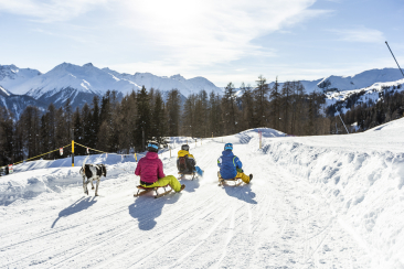 Familie beim Schlitteln mit Hund