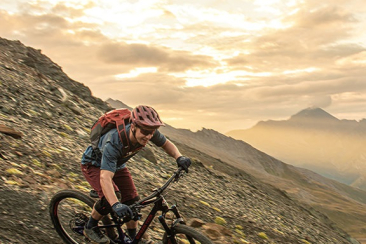 Mountainbiker fährt Trail in den Bergen um Scuol im Sonnenuntergang
