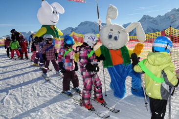 Kinder und Maskottchen der Skischule Scuol